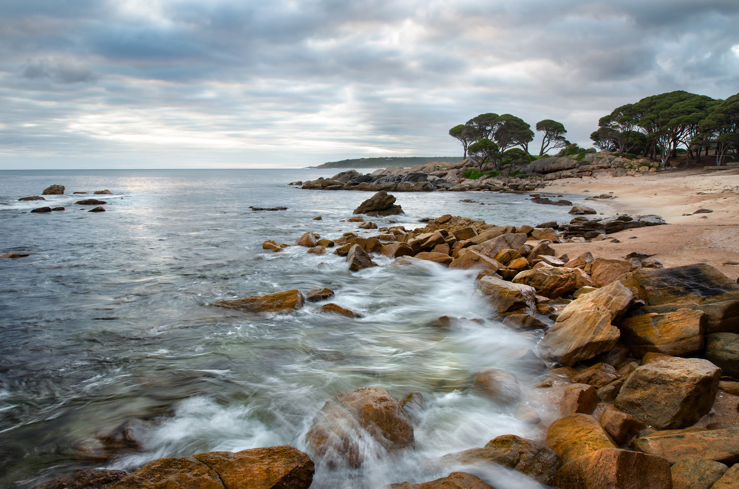 Textured rock edging the shoreline as dawn awakens.