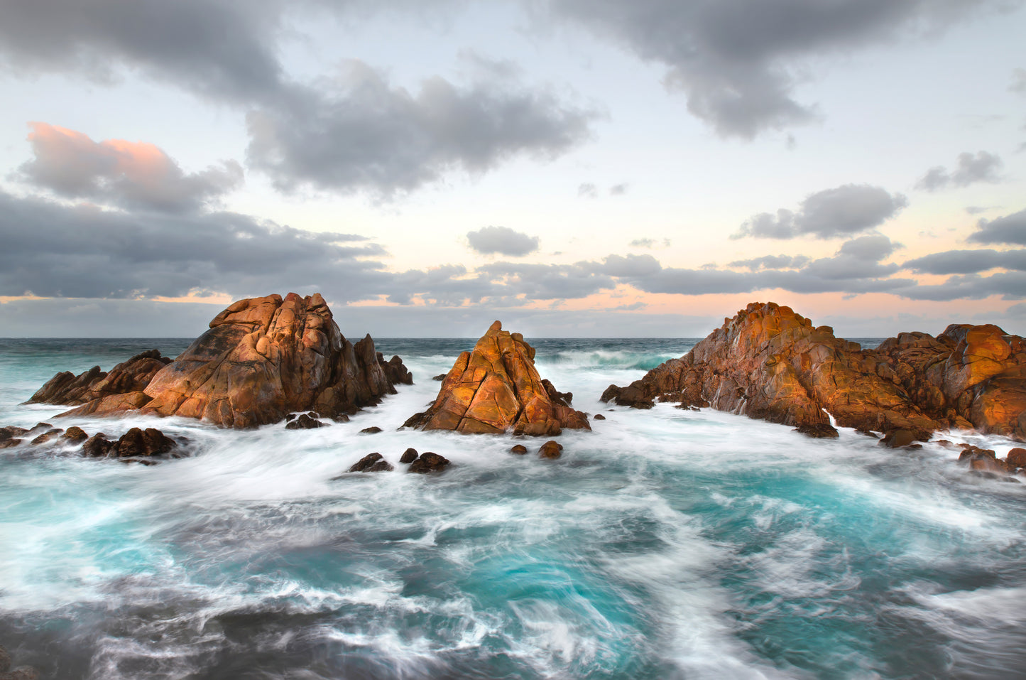 Natural light reflecting on rock formations, surrounded by swirling turquoise water.