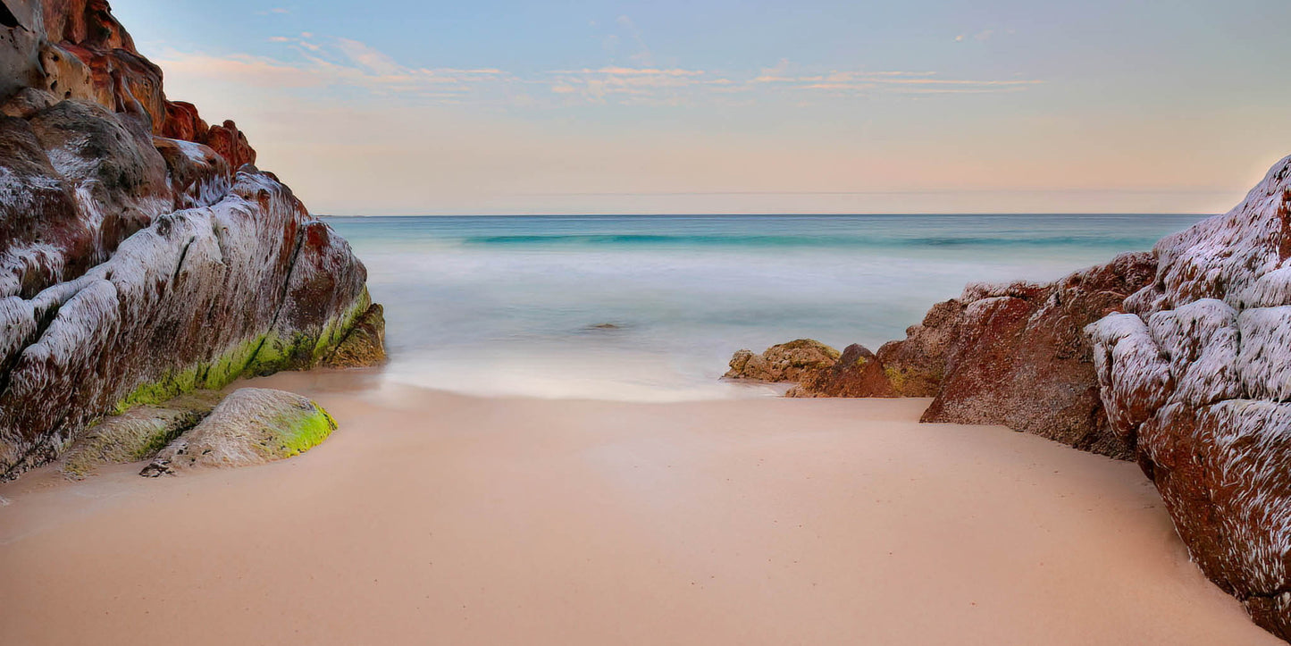 Beach scene with rocks and ocean under a clear sky
