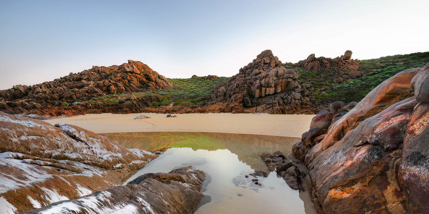 Rugged coastal landscape with rocks and a sandy beach.