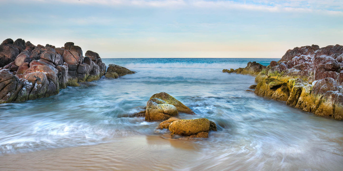 Rocks and waves on a beach with a clear sky