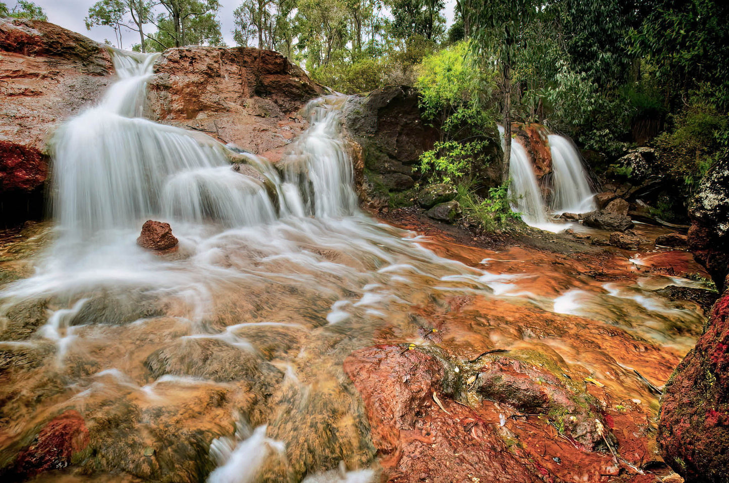 Waterfall cascading over colorful rocks in a lush forest