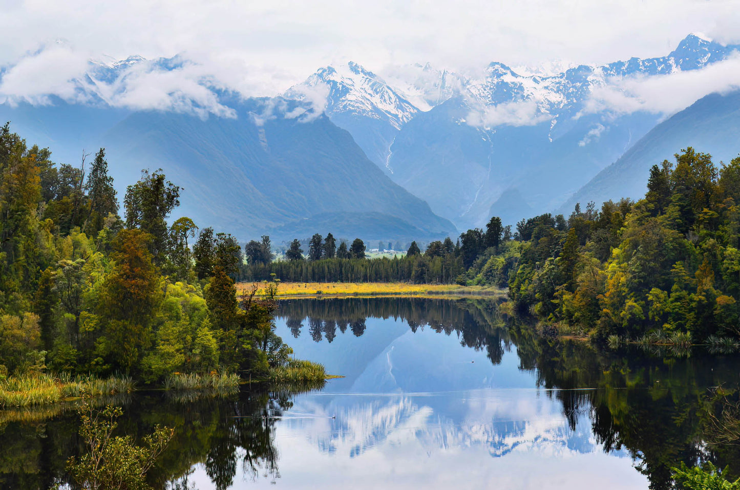 Lake with snowcapped mountains and trees reflecting in the water