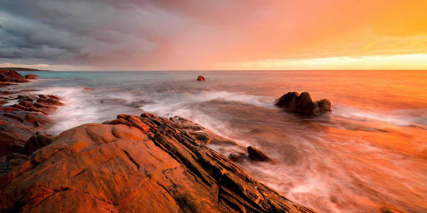 Colourful sunrise with storm over a rocky coastline with long exposure effects.