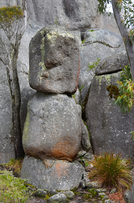 Stack of large gray stones with a face-like formation in a natural setting