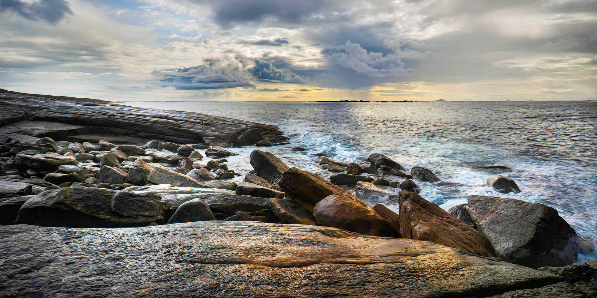 Rocks on a rocky shore with ocean waves and cloudy sky