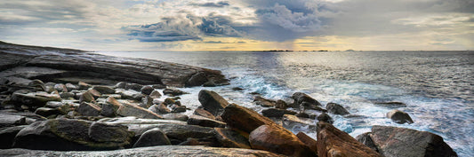 Storm brewing by a rocky coastline with ocean waves and a cloudy sky.