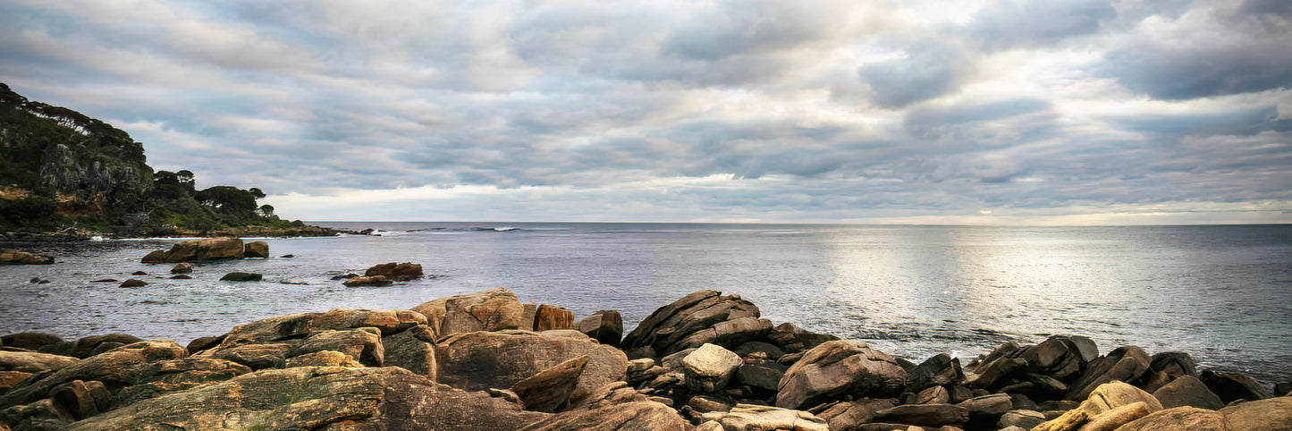 Rocks by a body of water under a cloudy sky