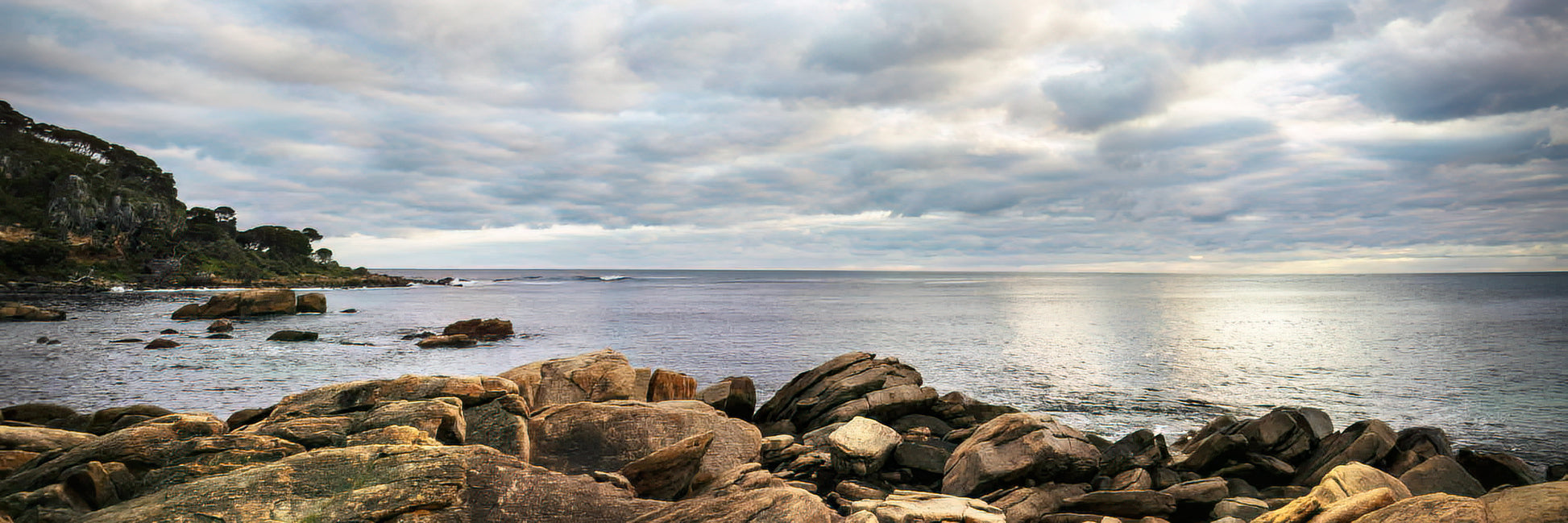 Rocks by a body of water under a cloudy sky
