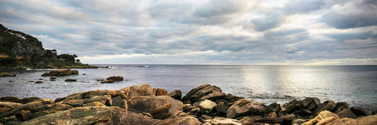 Rocks by a body of water under a cloudy sky