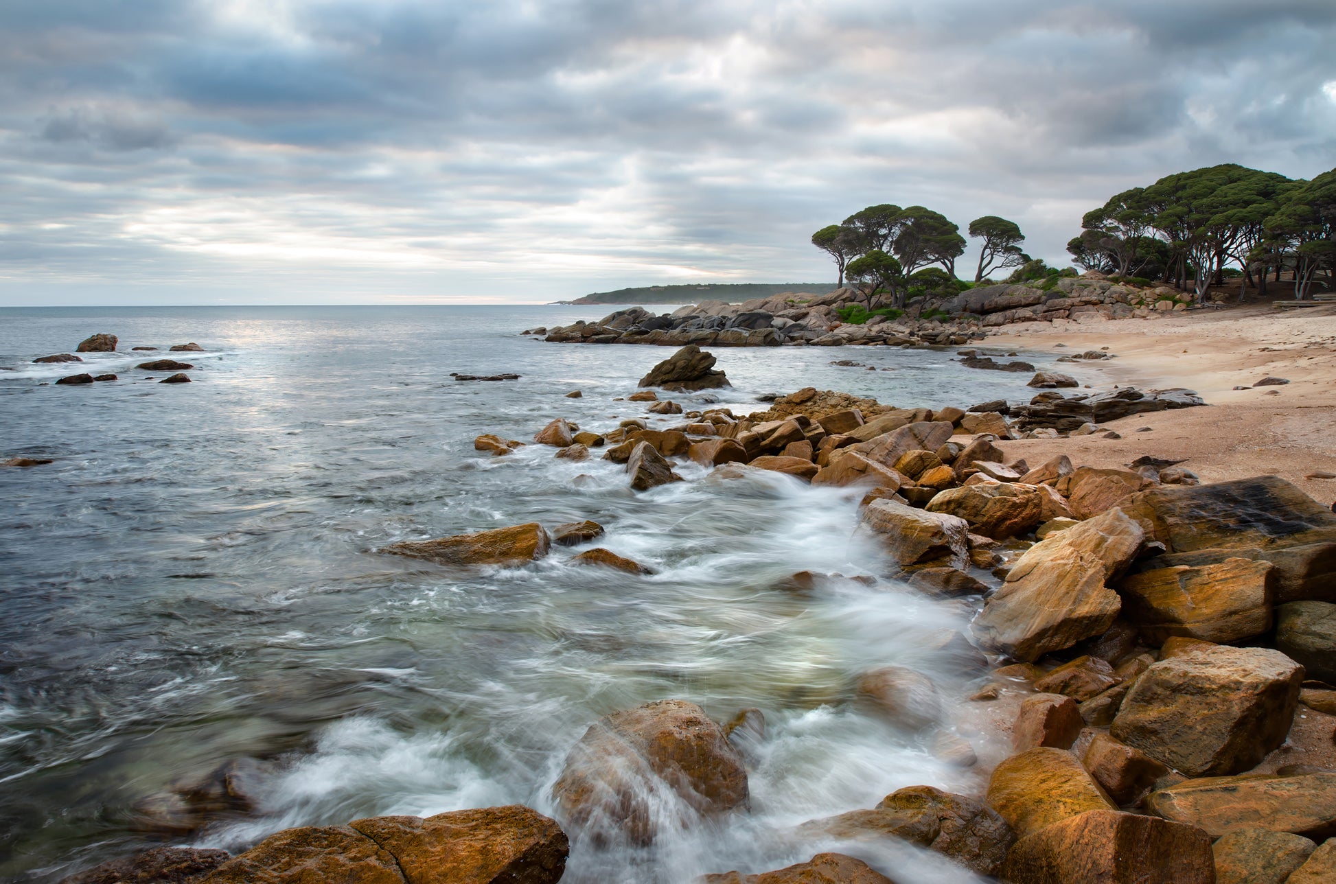 Textured rock edging the shoreline as dawn awakens.