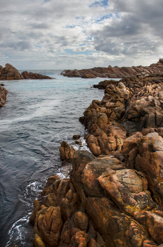 Warm tones shaping the rugged coastal landscape under a brewing sky at Canal Rocks.