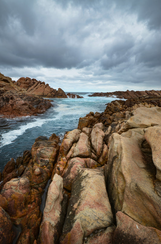 Dark, moody tones over Canal Rocks as a storm intensifies with atmospheric contrast between sky and stone.