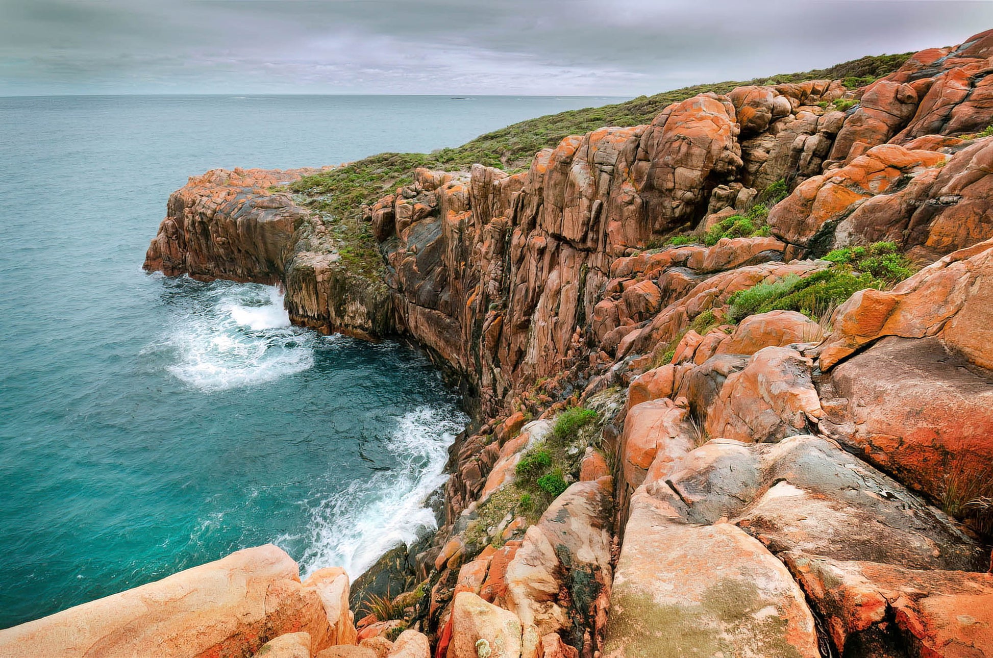 Rugged coastline with rocky cliffs and turquoise water on a cloudy day
