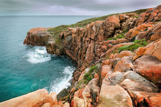 Rugged coastline with rocky cliffs and turquoise water on a cloudy day