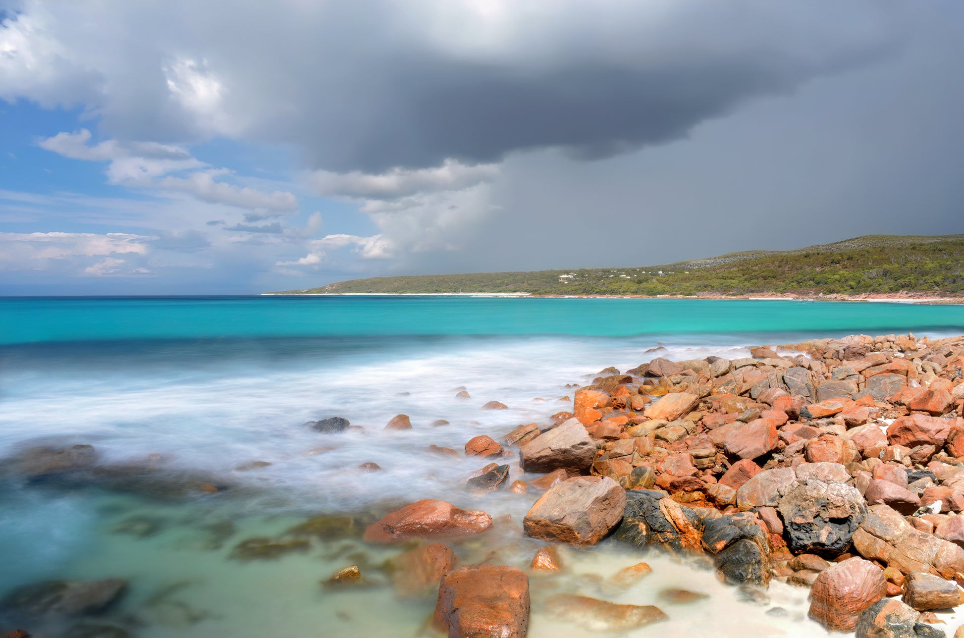 Moody clouds over bright turquoise water at Eagle Bay headland.
