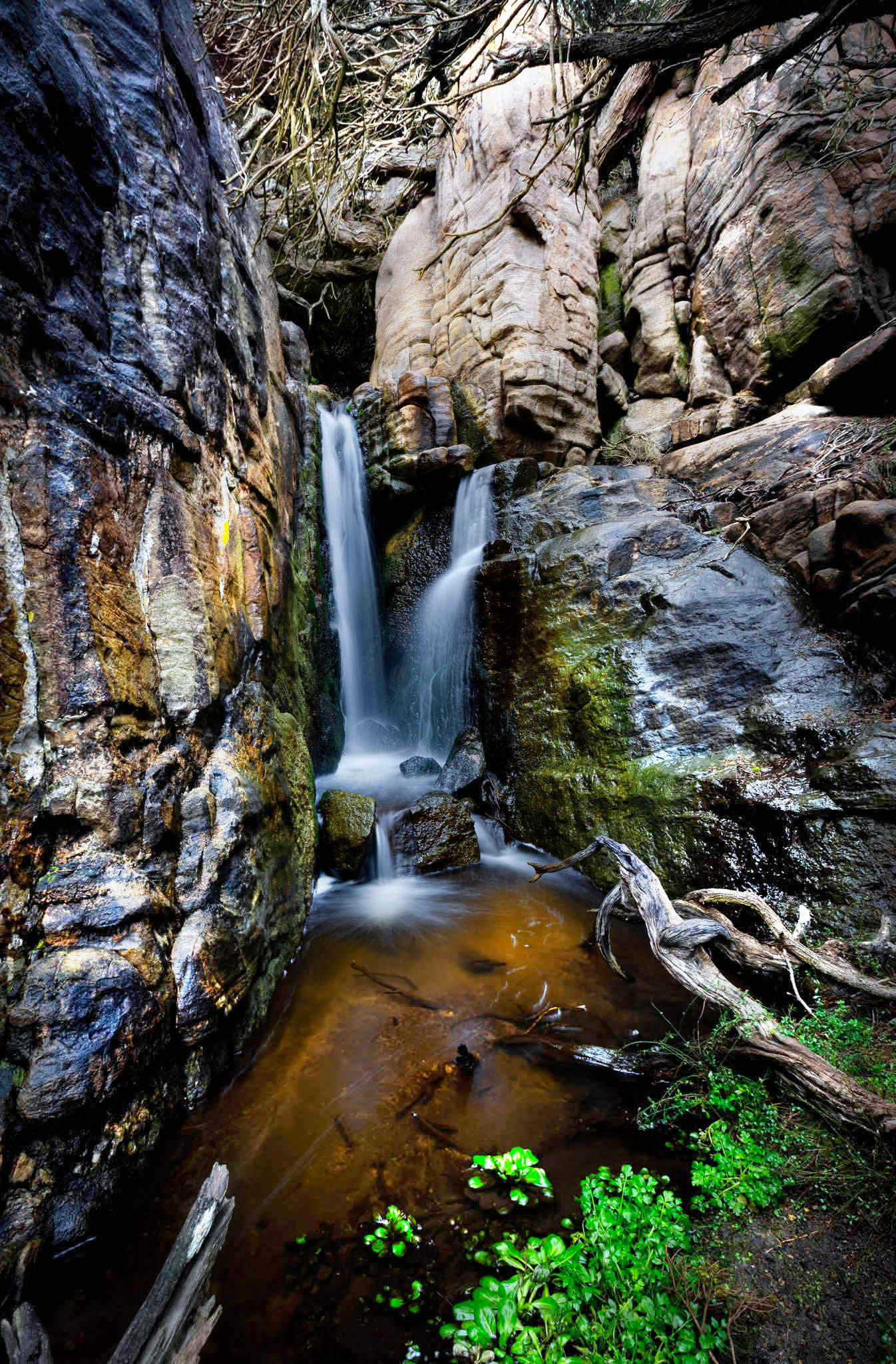 Waterfall cascading down rocky cliffs with greenery