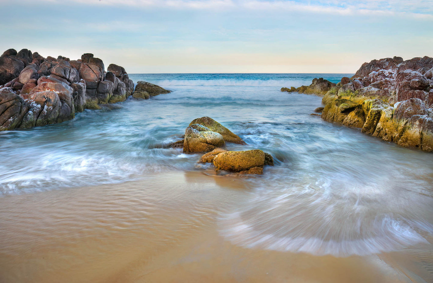Beach scene with rocks and waves at dawn