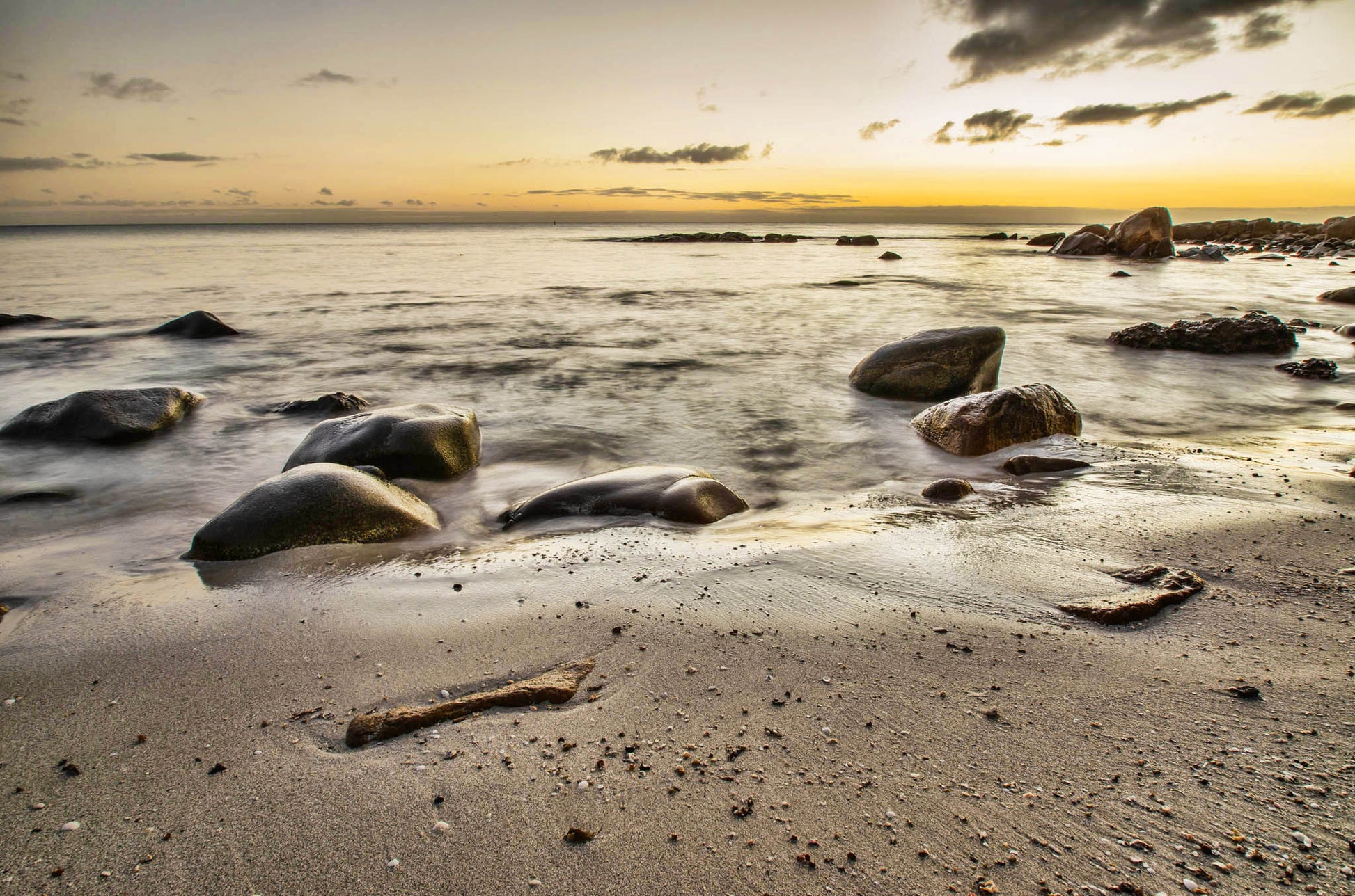 Beach scene with rocks and a sunrise over the ocean
