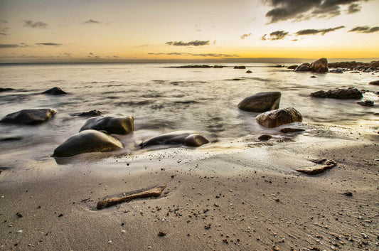 Beach scene with rocks and a sunrise over the ocean