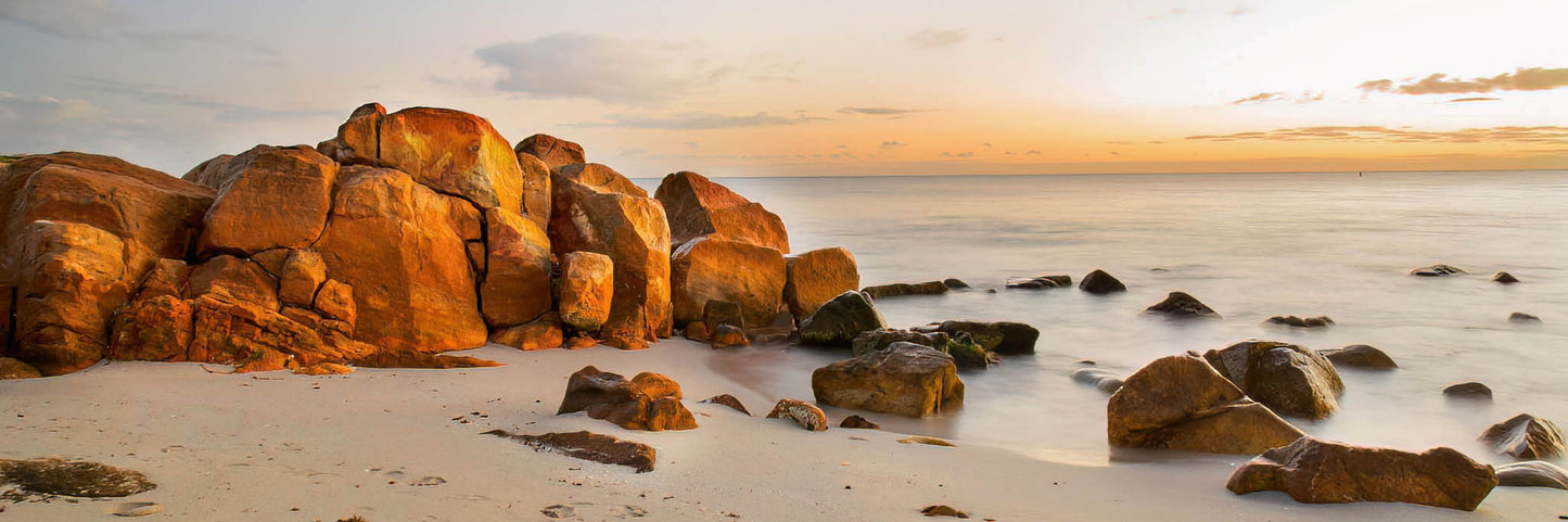Rocks at Meelup Beach during sunrise with calm ocean waters.