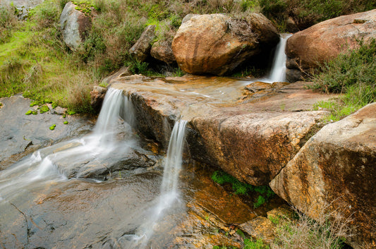 Stream flowing over rocks with greenery in the background