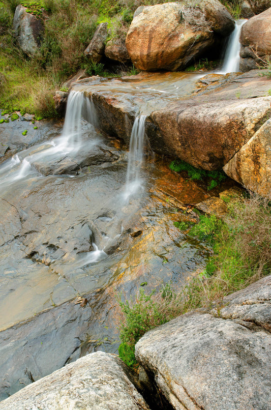 Stream flowing over rocks with waterfalls in a natural setting