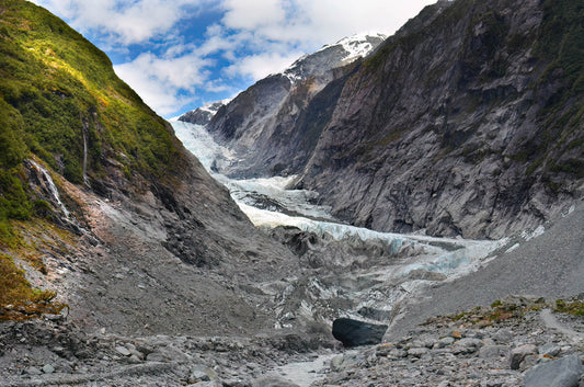 Glacier flowing through a valley with mountains in the background