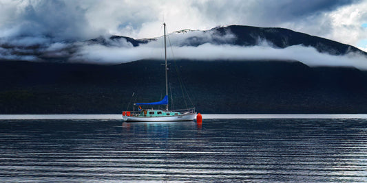 Yacht on a lake with long white clouds above.