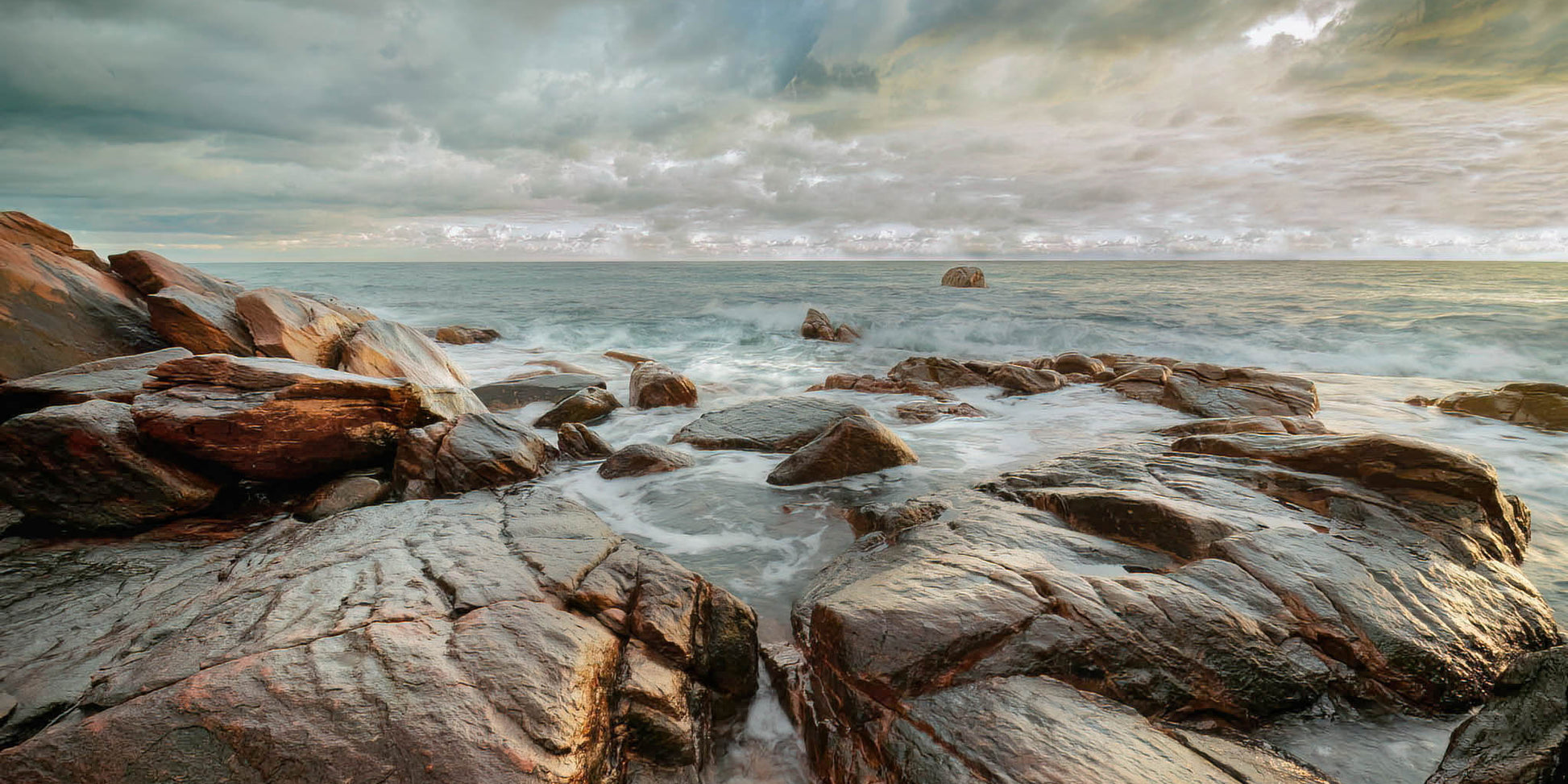 Rocky coastline by the sea under a cloudy sky at Point Picquet.