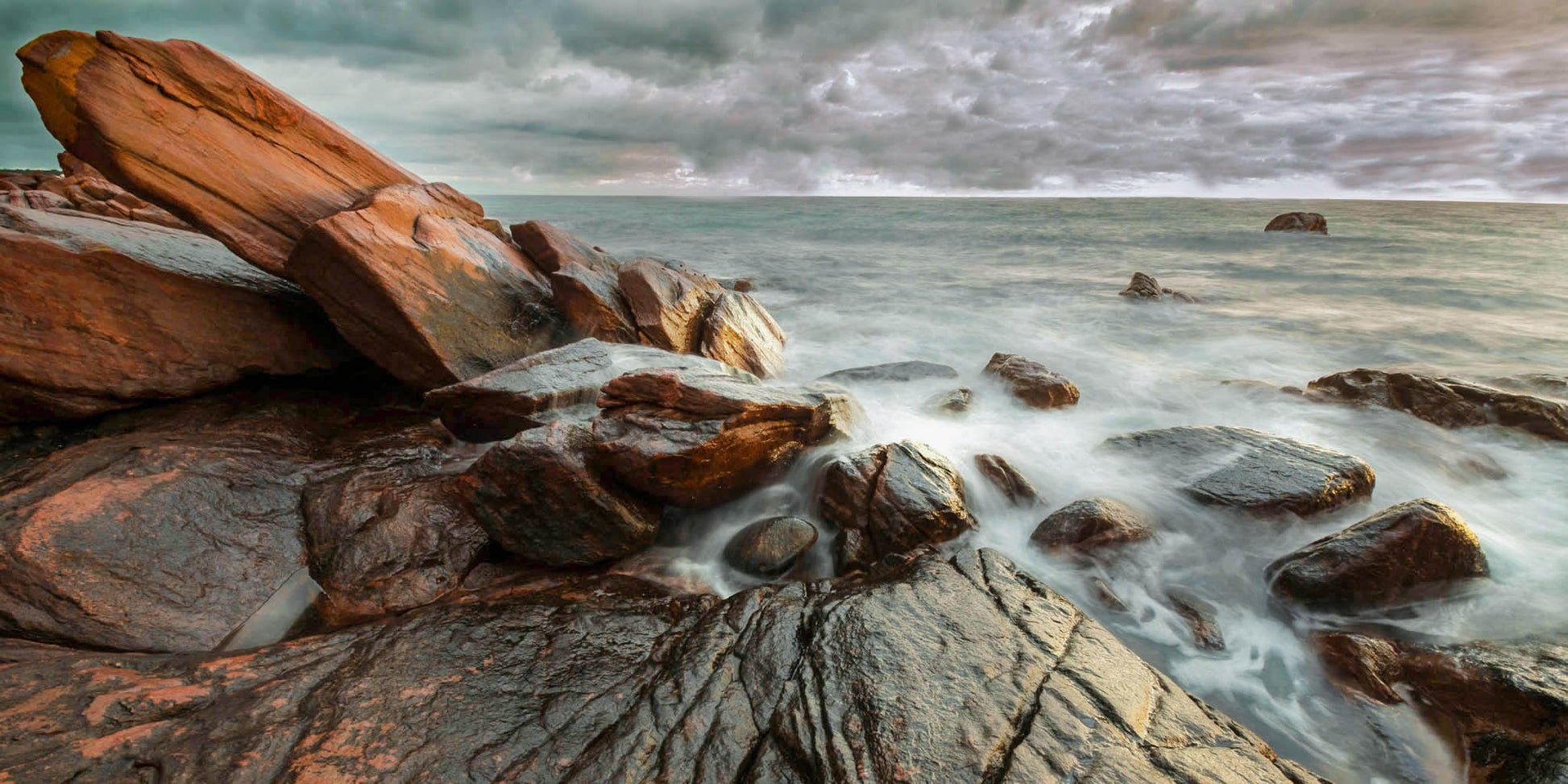 Rock formations balanced together by the sea with a stormy sky