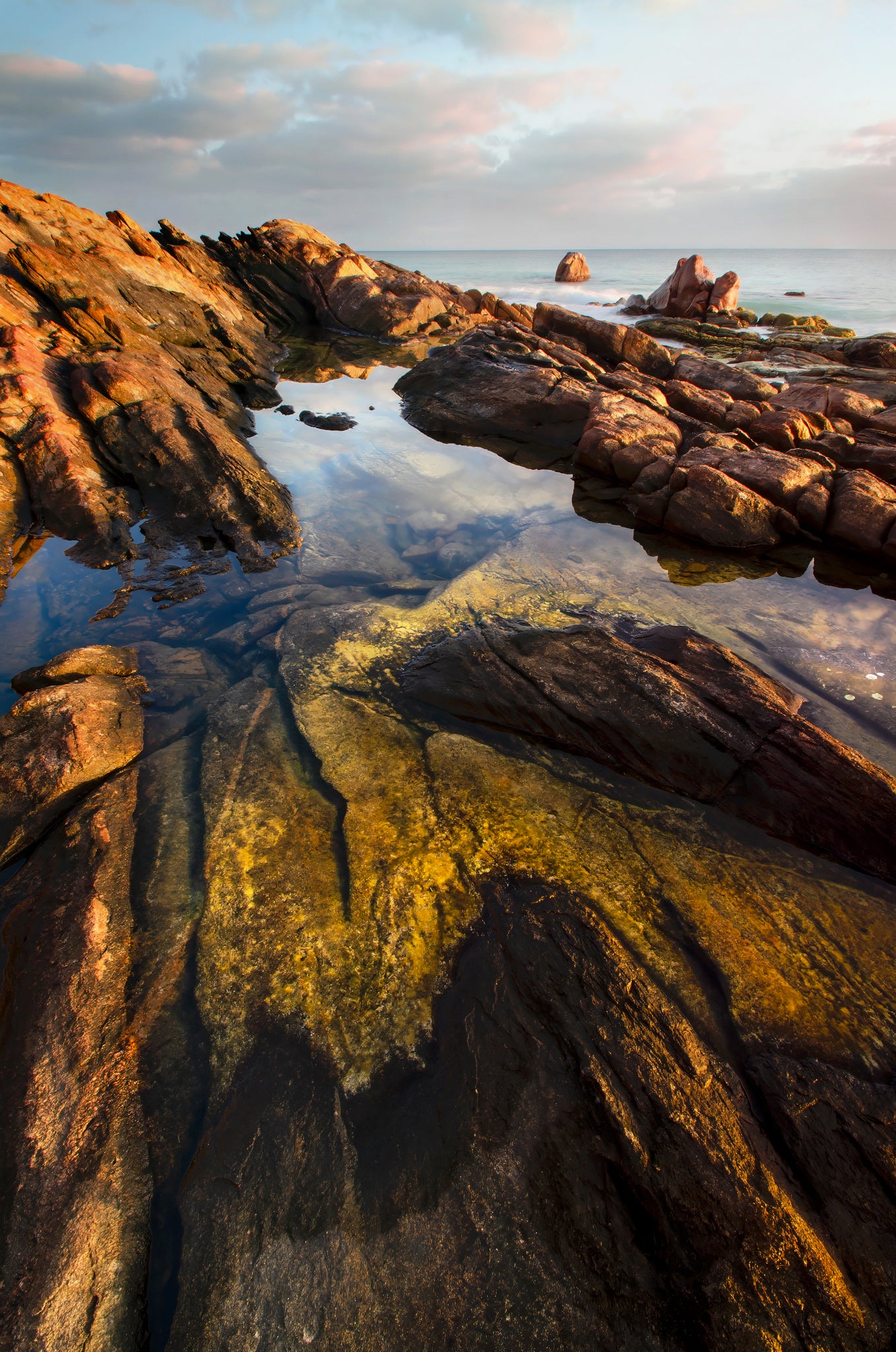 Amber hues at dawn, with crystal clear water in a pool surrounded by textured granite.