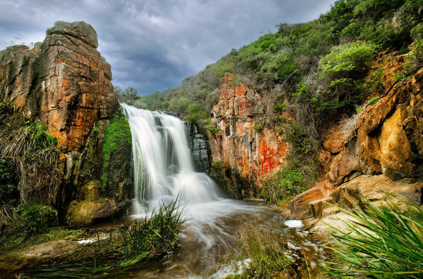 Overcast moody scene of Quinninup Falls surrounded by rugged terrain.