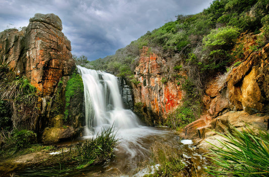 Overcast moody scene of Quinninup Falls surrounded by rugged terrain.