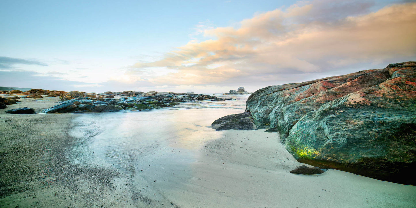 Redgate Beach scenic view with colourful rocks and water under a cloudy sky.