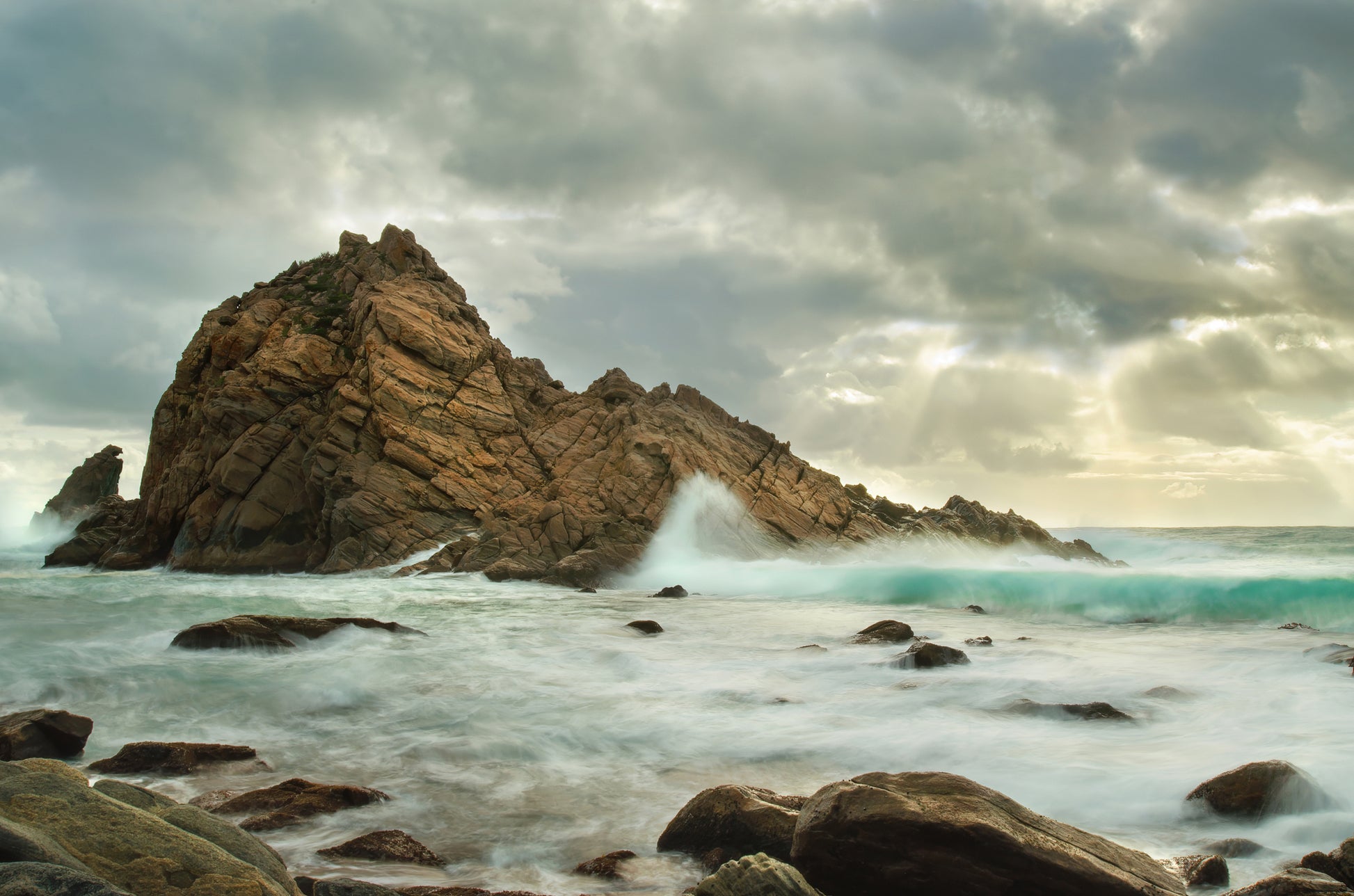Powerful Indian Ocean waves surging around Sugarloaf Rock during high tide.