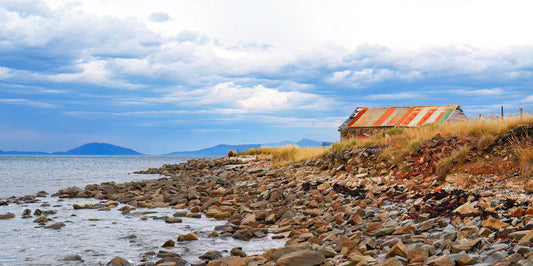 old boat shed on lakeside with cloudy sky