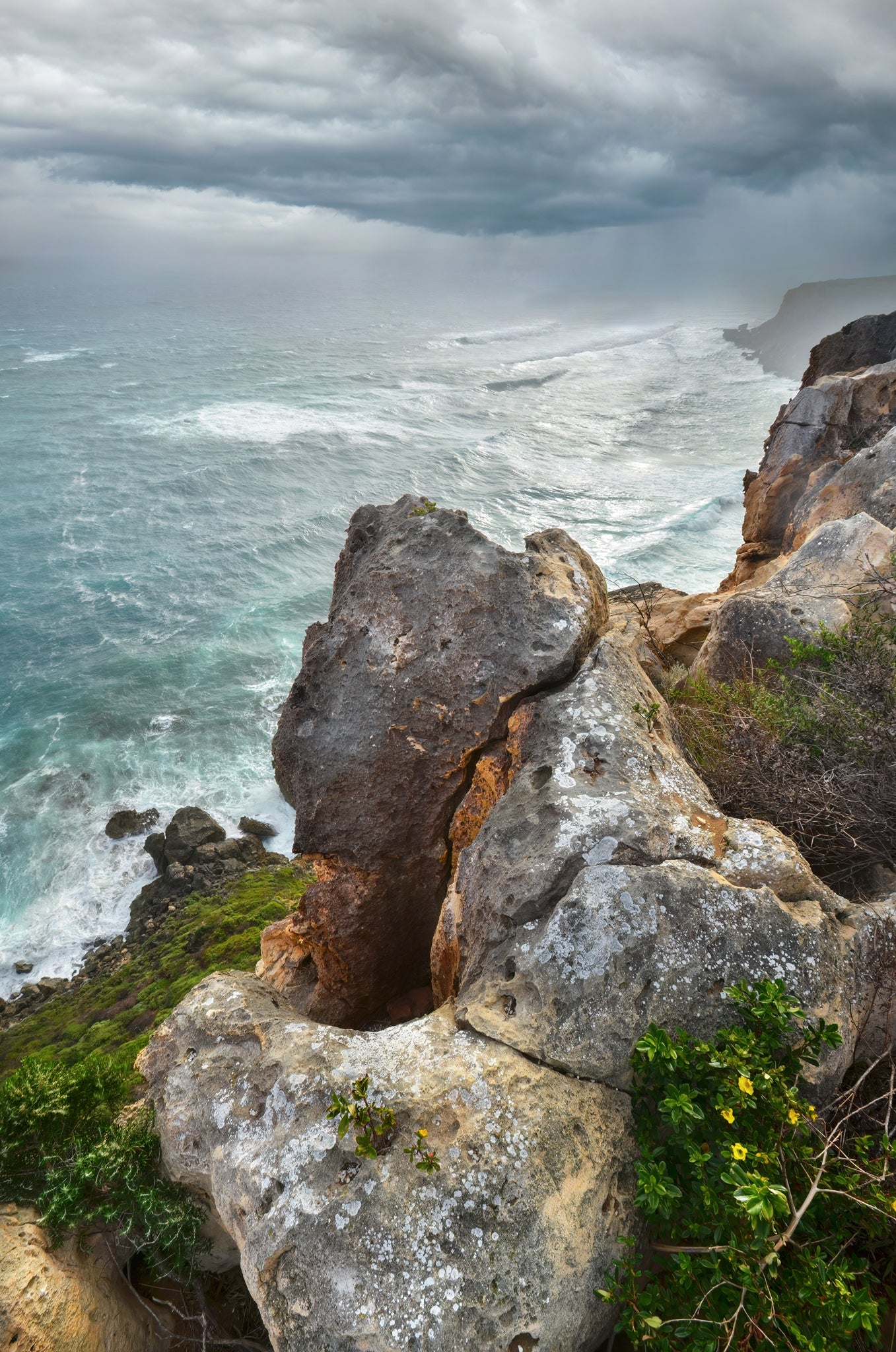 Dark storm clouds rolling over the coastline with heavy rain sweeping across the horizon.